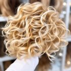 Peruka falowana z grzywką, afroloki - 63353c jasny ciepły blond -R21T-na większe głowy Peruka falowana z grzywką, afroloki - 63353c jasny ciepły blond -R21T-na większe głowy